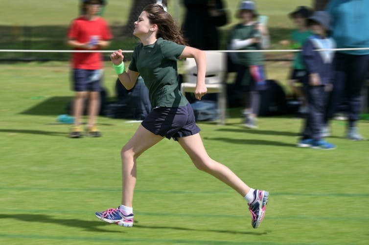 A girl in green runs.