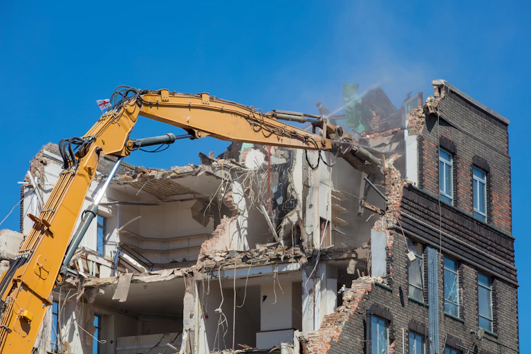 A long-armed demolition machine takes apart a multistorey building.