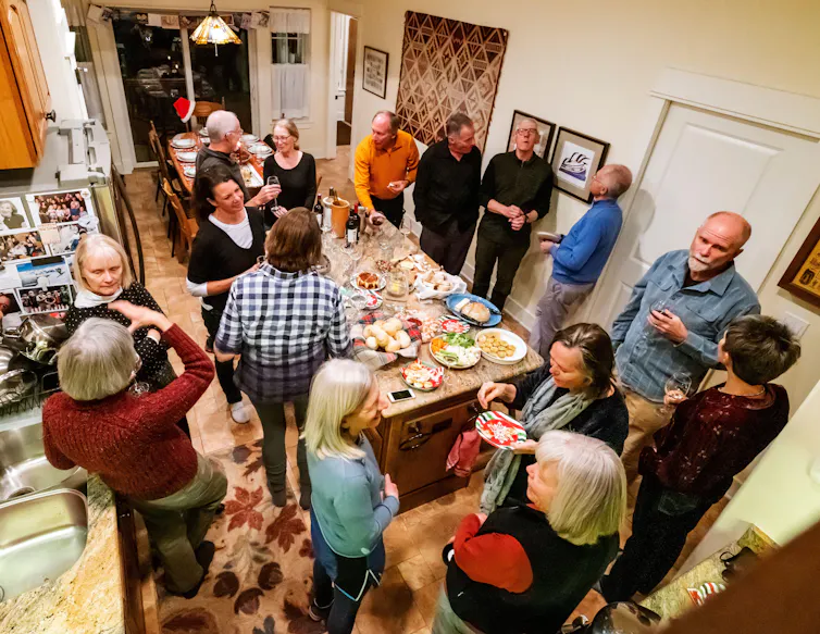 A group of people stand in a room together talking.
