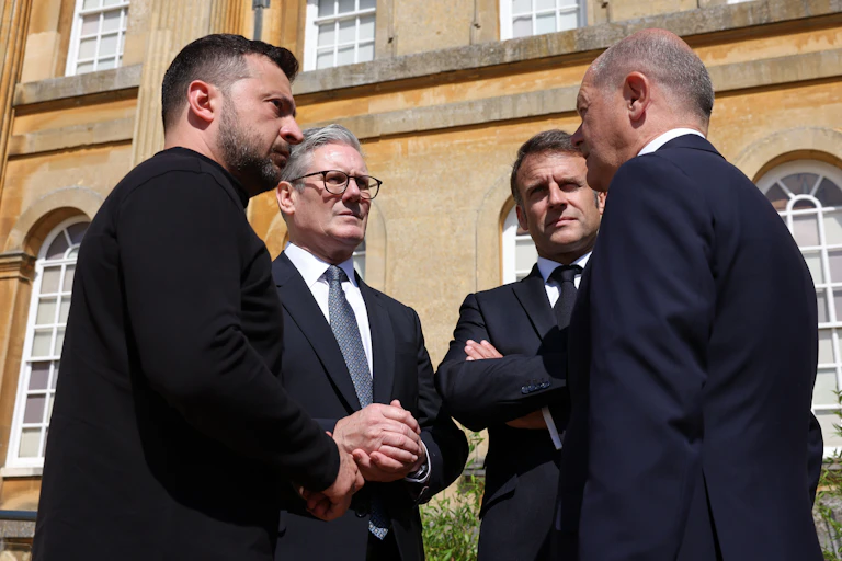 View from below looking up at Zelensky, Starmer, Macron and Scholz standing in a circle outside Blenheim Palace