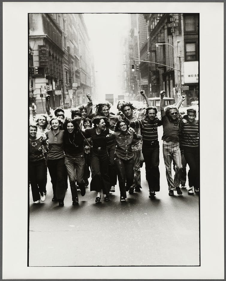 Imagen del póster del Gay Liberation Front en 1970, en donde un grupo de jóvenes camina por la calle abrazados.