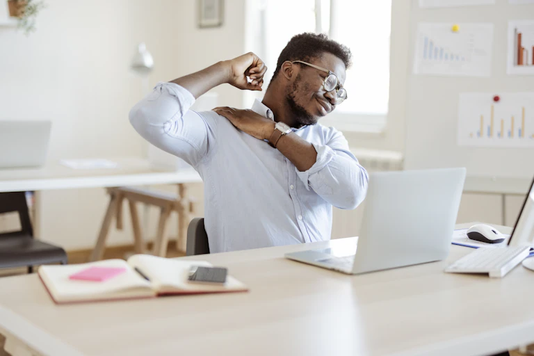 Man with back pain stretches at desk