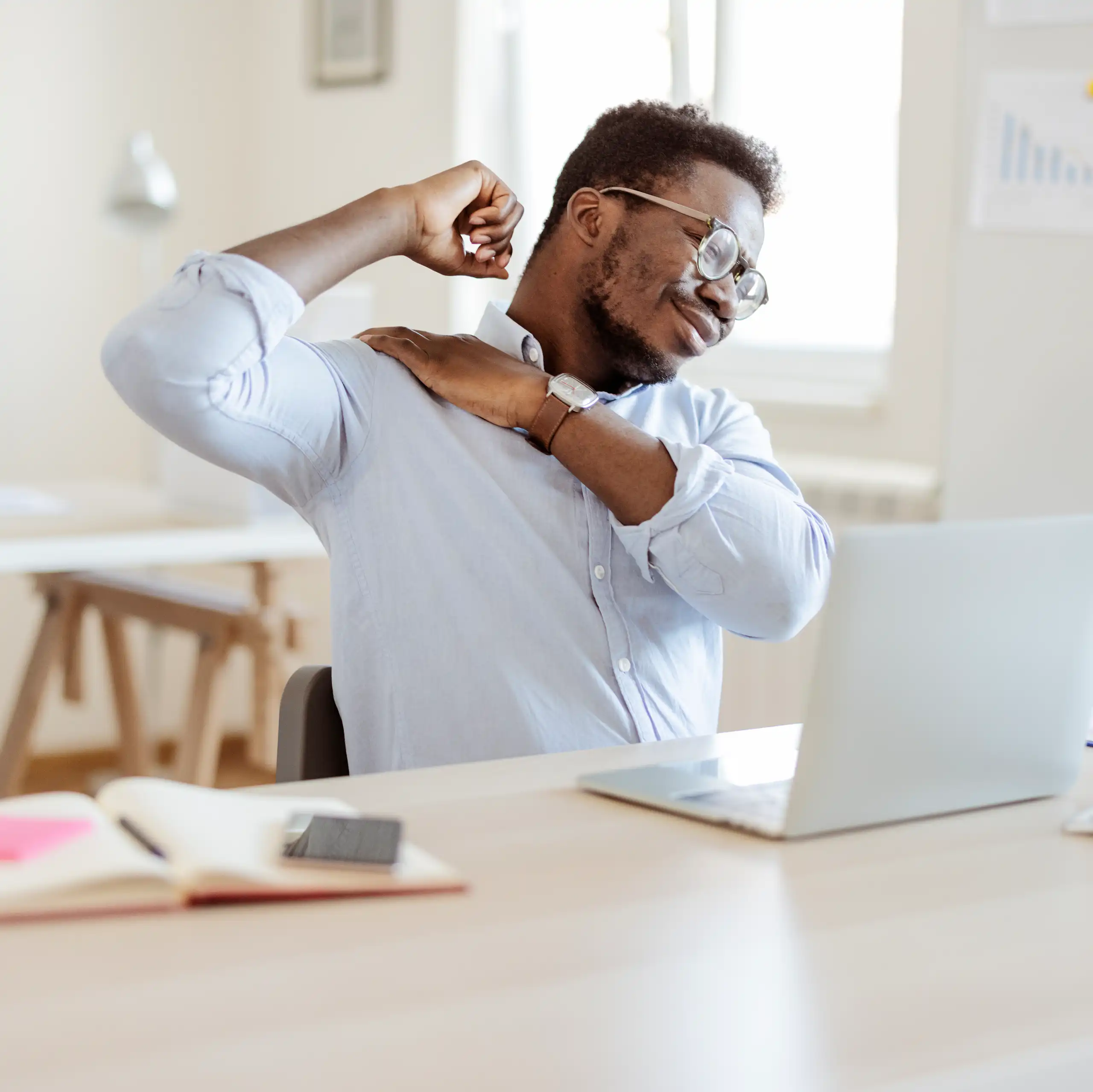 Man with back pain stretches at desk
