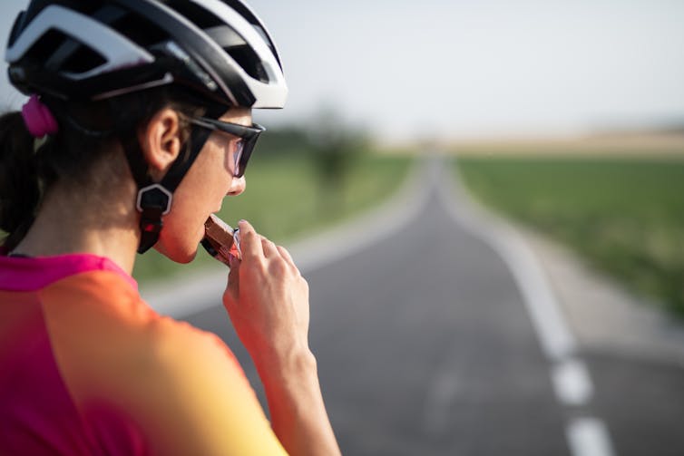 Cyclist eating protein bar, looking out at the road