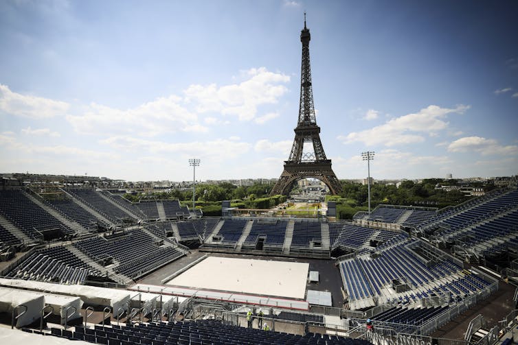 A sand court with bleachers on all sides and the Eiffel Tower in the background.