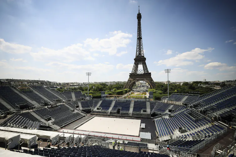 A sand court with bleachers on all sides and the Eiffel Tower in the background.