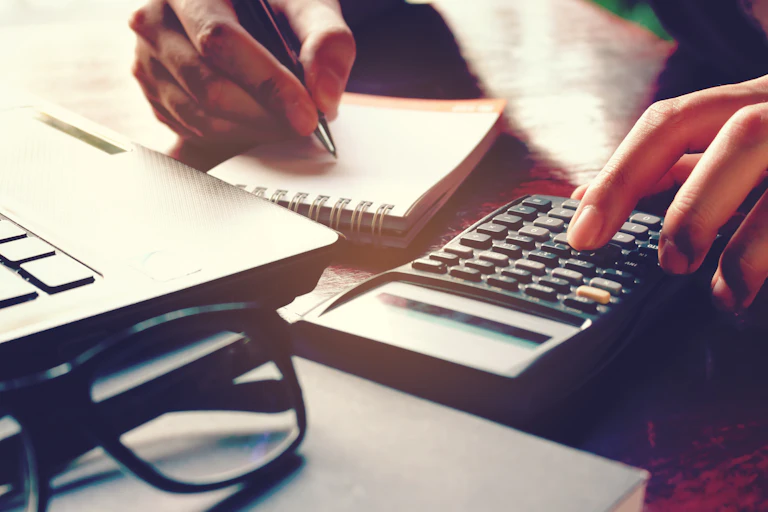 pad and calculator of someone writing a budget