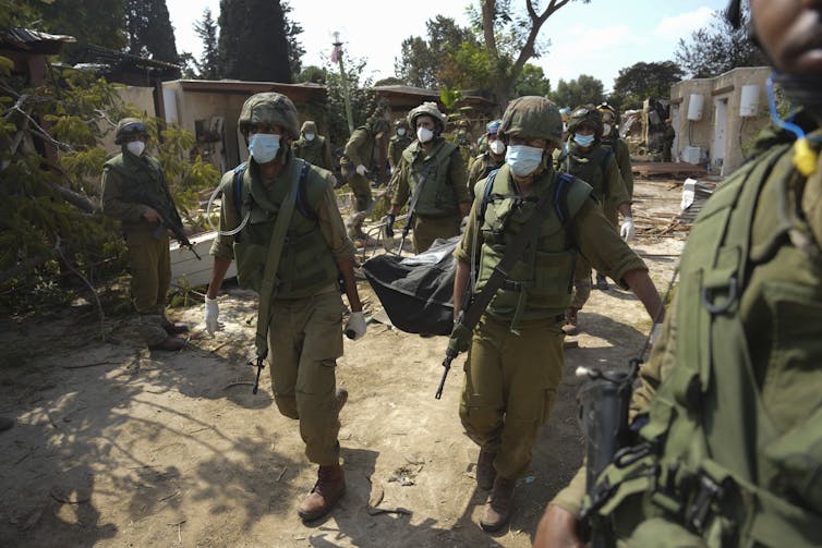 Soldiers wearing masks carry a body