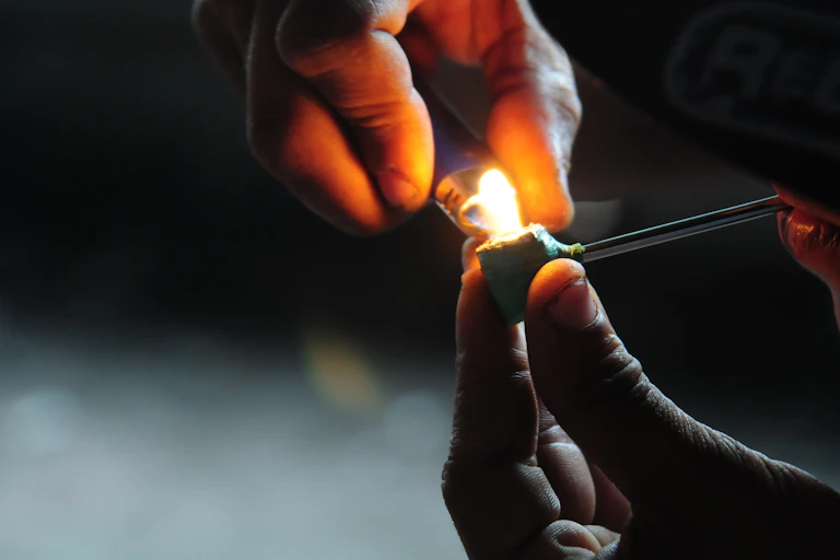 two hands are seen lighting up a pipe