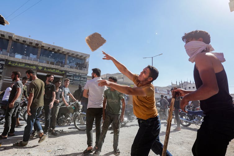 Protestor throws a rock at a truck.