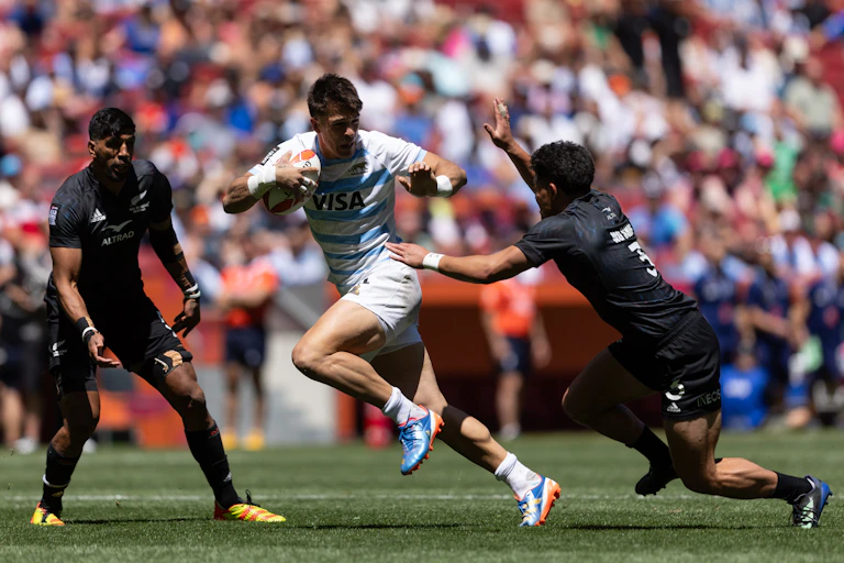 Argentinian rugby sevens player evading tackle by New Zealand player