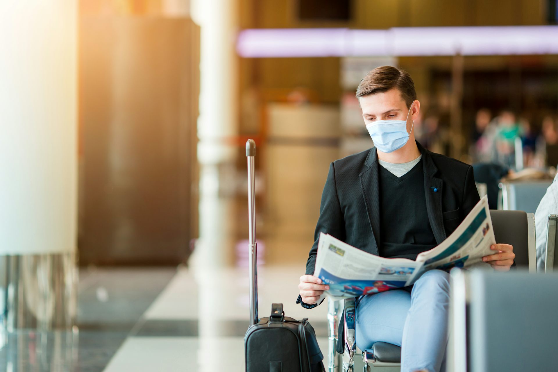 A man in an airport wearing a mask.