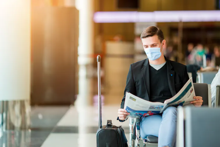 A man in an airport wearing a mask.