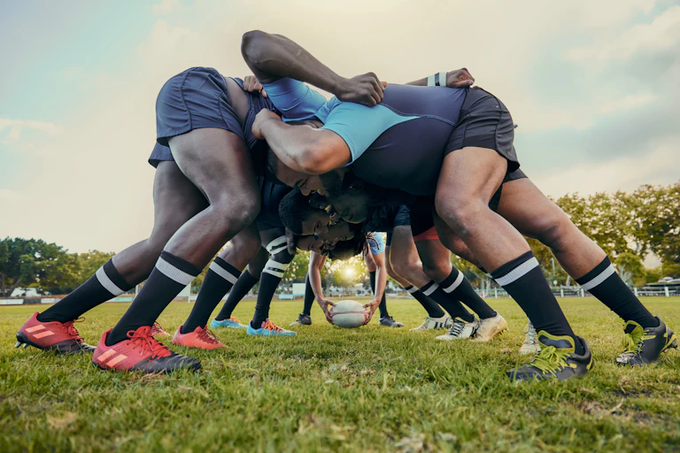 Des joueurs de rugby dans une mêlée avec un ciel gris.
