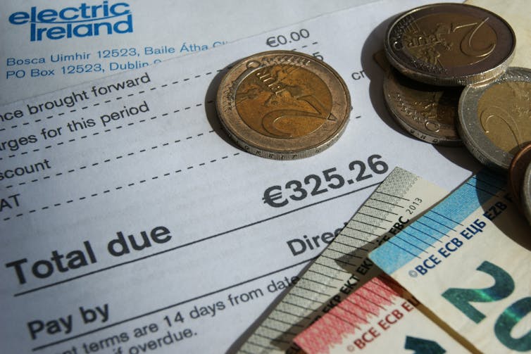 Euro coins and notes on top of an electricity bill.