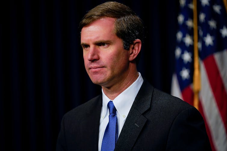Andy Beshear in front of an American flag