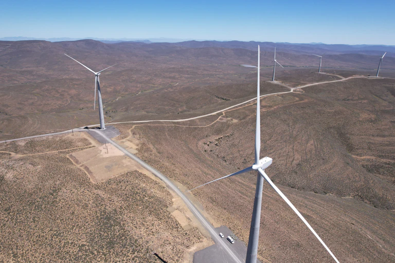 Several giant wind turbines dot a dry and dusty landscape
