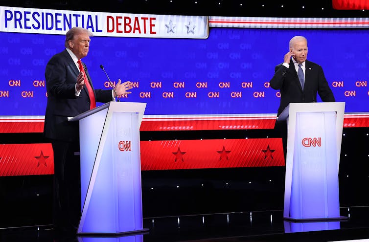 Two men in suits at lecterns that say 'CNN' on them.
