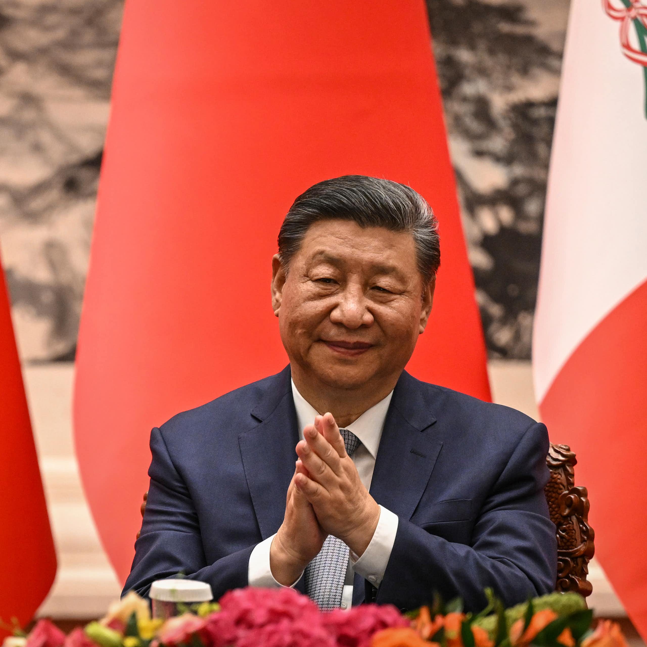 Un homme assis devant des drapeaux applaudit