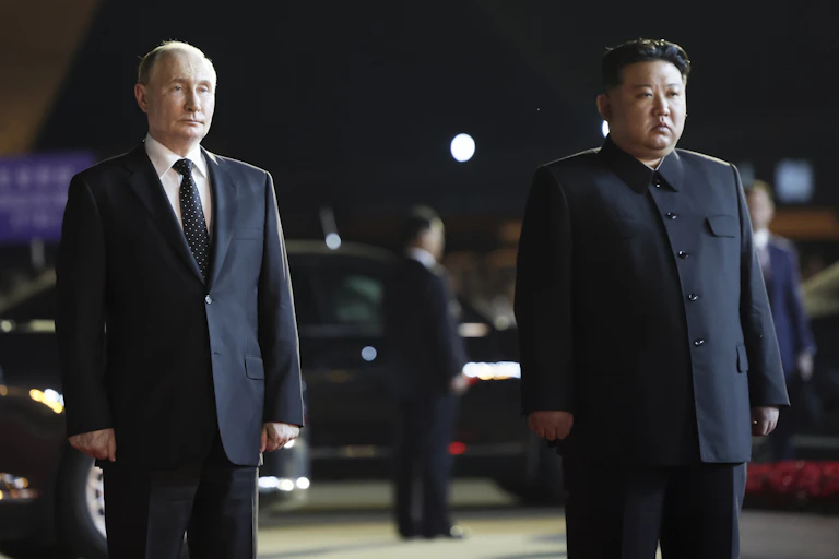 Two men, one a balding white man and another a rotund Asian man, stand side by side on an airport tarmac.