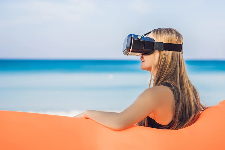 woman wearing virtual reality headset, sitting on orange seat, blue sea and sky in background