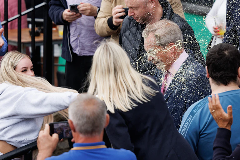 a woman throwing a milkshake at Nigel Farage