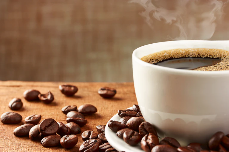 A coffee cup and saucer with coffee beans