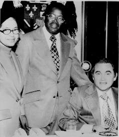 Parks and Gray stand beside a seated Wallace at a desk.