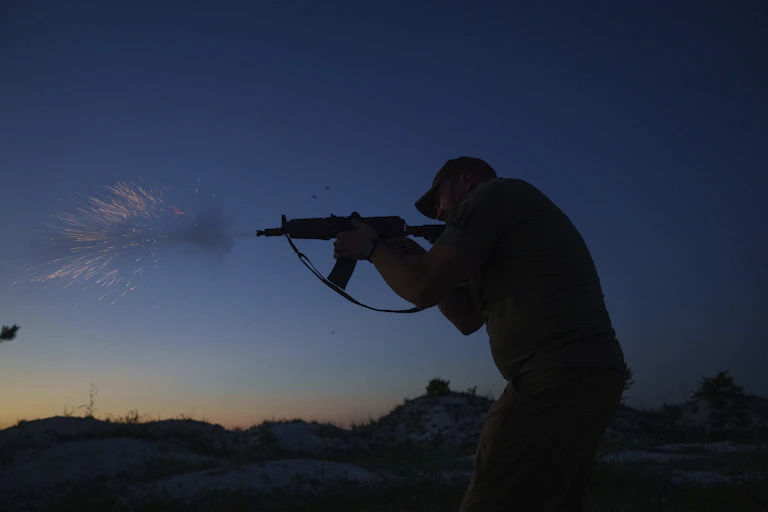 Un soldat envoie une salve dans les airs, au coucher du soleil