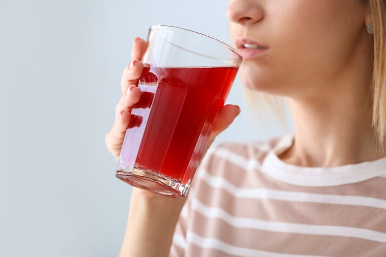 woman sips from large glass of red juice