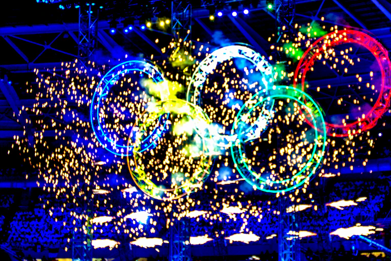 Olympic rings illuminated by fireworks.