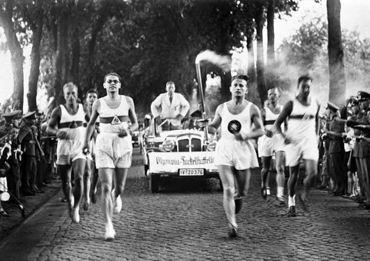 Black and white photo of runners carrying the Olympic torch