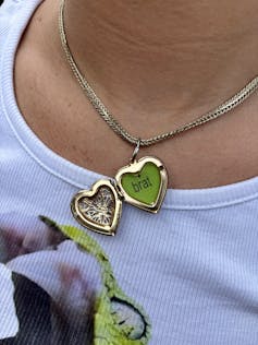 A locket open to show the cover art for Brat inside.