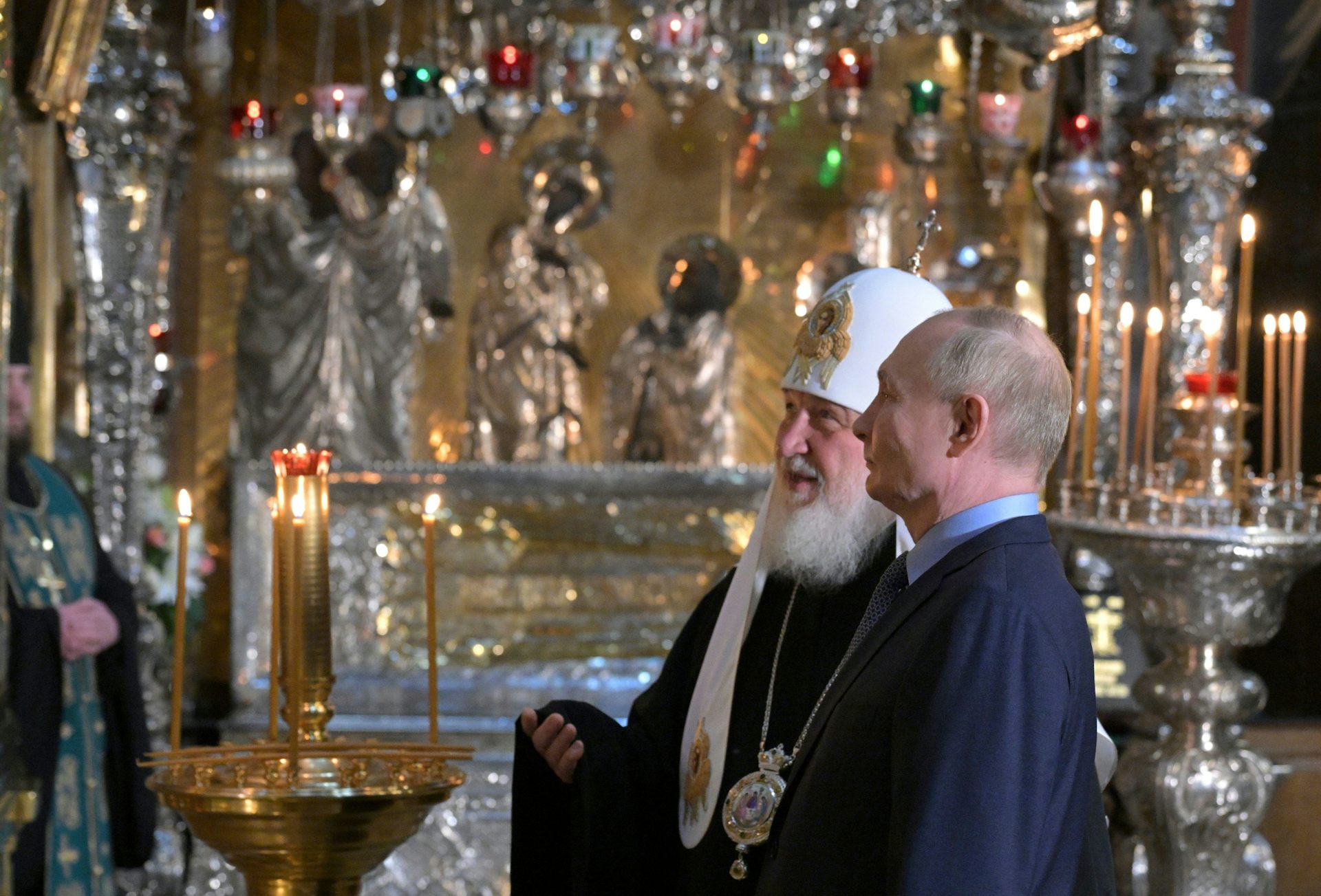 Russian president Vladimir Putin, right, accompanied by Russian Orthodox Patriarch Kirill visits to the Trinity Cathedral otuside Moscow. They are standing talking to each other.