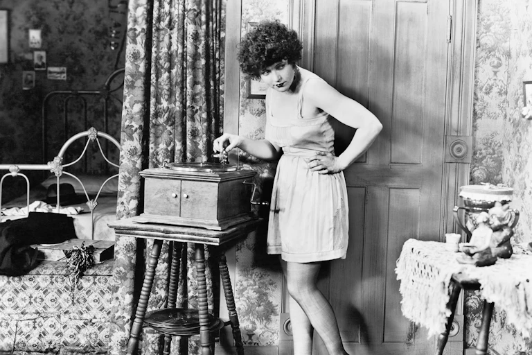 Una foto en blanco y negro de una mujer a punto de poner un disco en un reproductor antiguo.