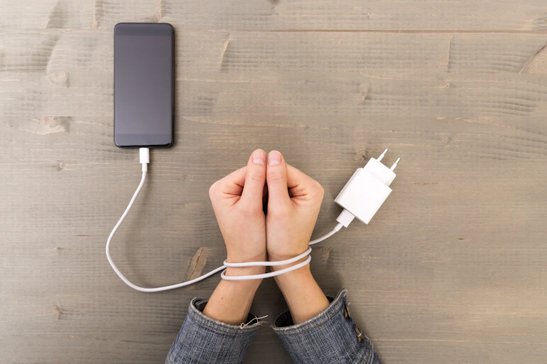 hands tied with smartphone charger cord