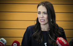 A dark-haired woman struggles to compose herself at a news conference.