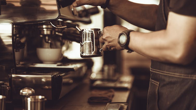 Closeup of barista steaming milk on an espresso machine