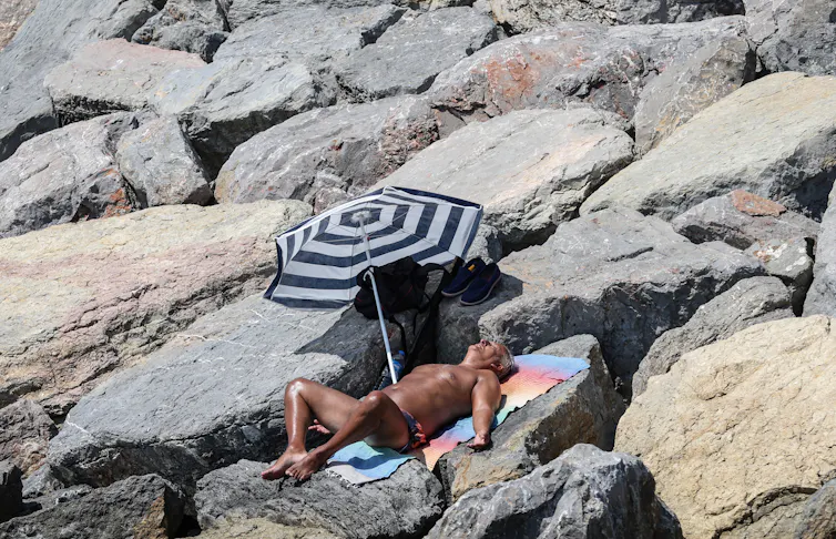 man lies in sun under umbrella