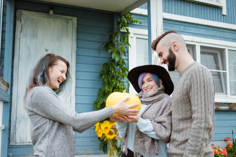 A woman is delighted at being given a pumpkin by a couple