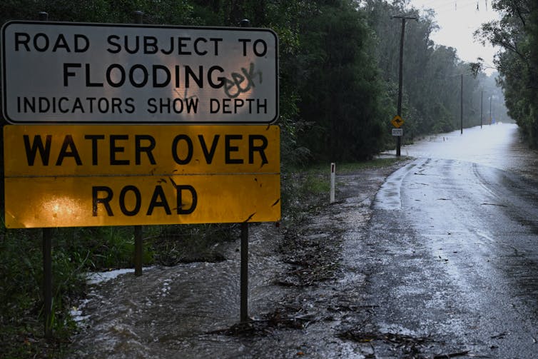 flooded road with sign reading 'Road subject to flooding; water over road'