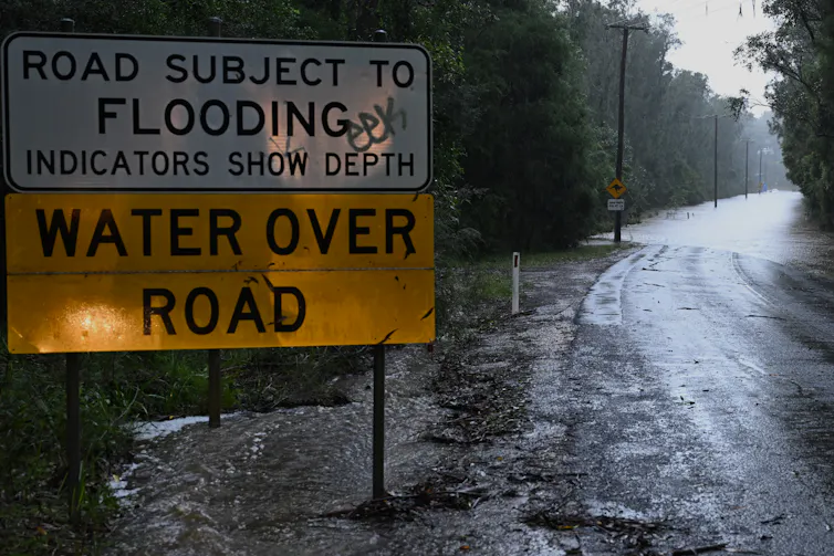 flooded road with sign reading 'Road subject to flooding; water over road'