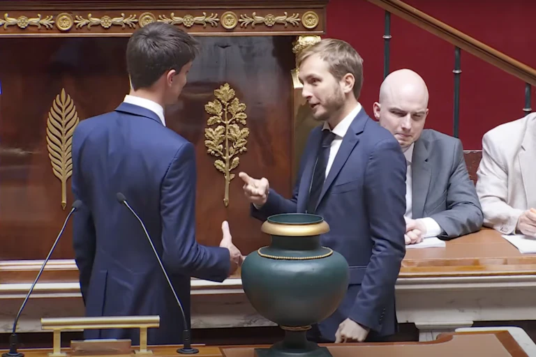 A man holding his hand out to shake and François Piquemal holding his hand in the shape of scissors in response.