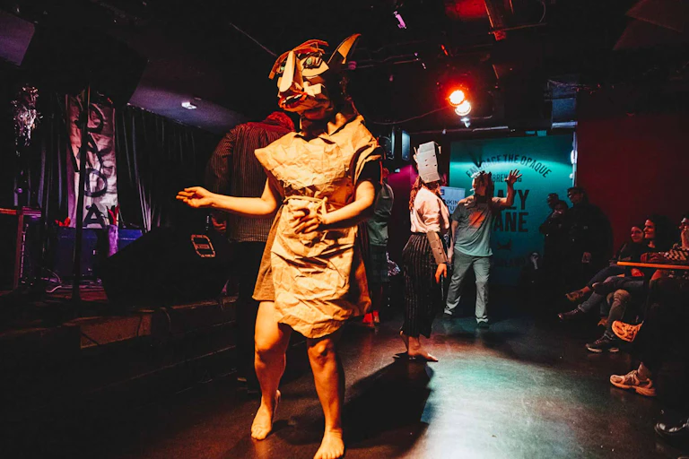 A woman dancing on a stage with a strange animal mask.