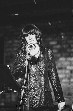 A woman in a sequin jacket performing on stage.