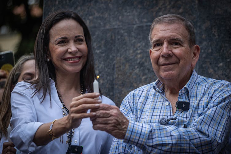 Edmundo González Urrutia and Maria Corina Machado smiling and together holding a candle in the air.