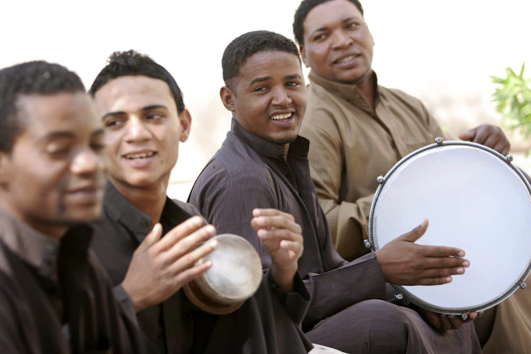 Men sit in a row playing drums