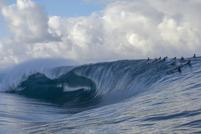 Surfers cresting breaking wave at Teahupo'o