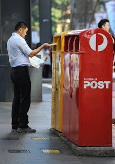man posting mail at an Australia Post postbox in Sydney