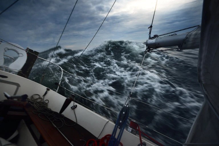 A boat is tossed around by big waves on a dark, stormy sea
